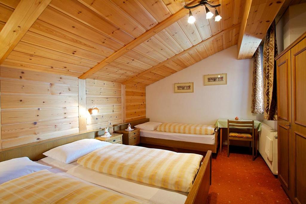 a bedroom with two beds in a wooden room at Angerle Alm Apt Zwergenvolk in Carezza al Lago