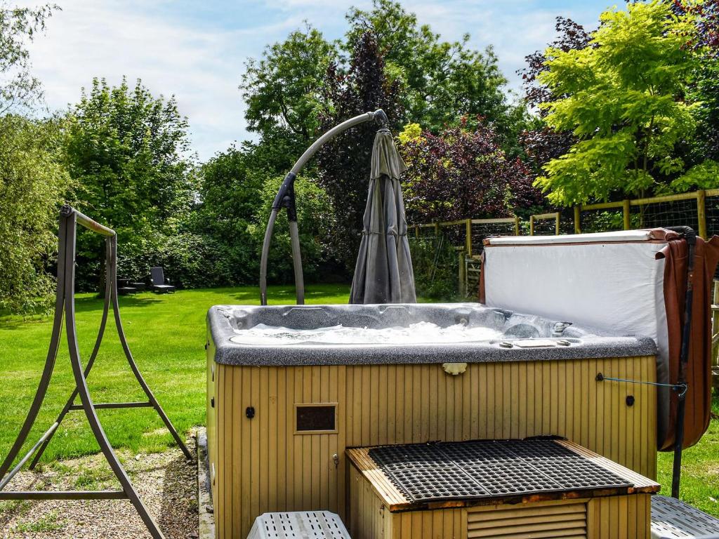 a hot tub in a backyard with an umbrella at Toms Cabin - Uk35173 in Elmsted
