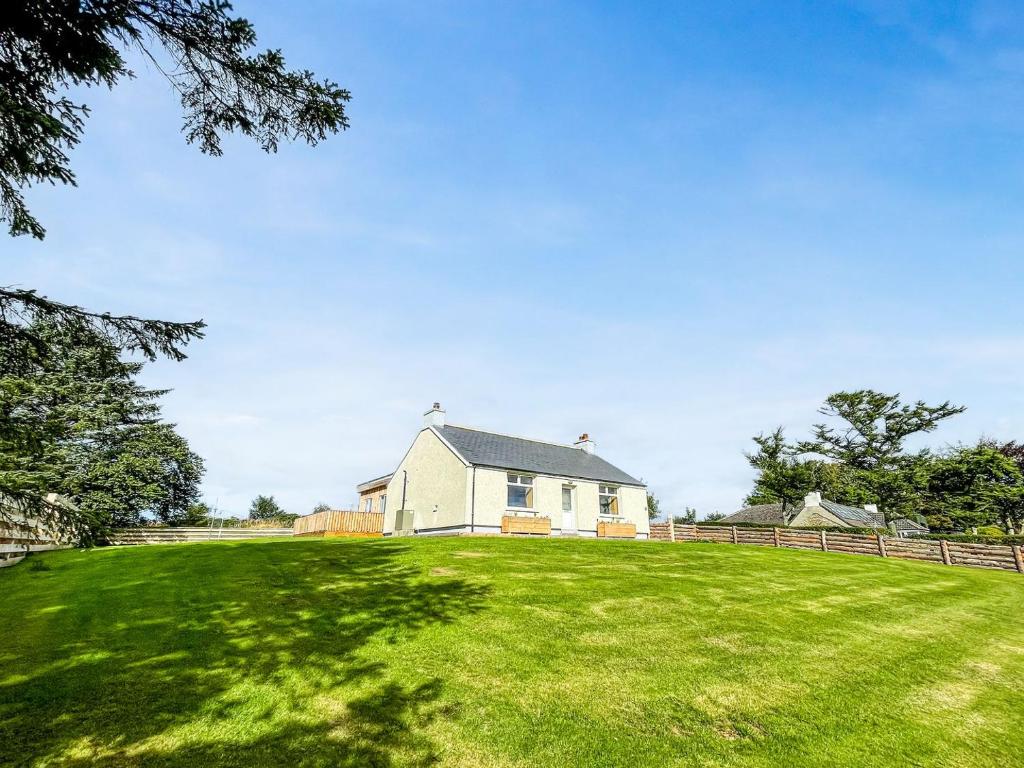 een wit huis op een grasveld bij Post Office Cottage in Skaill