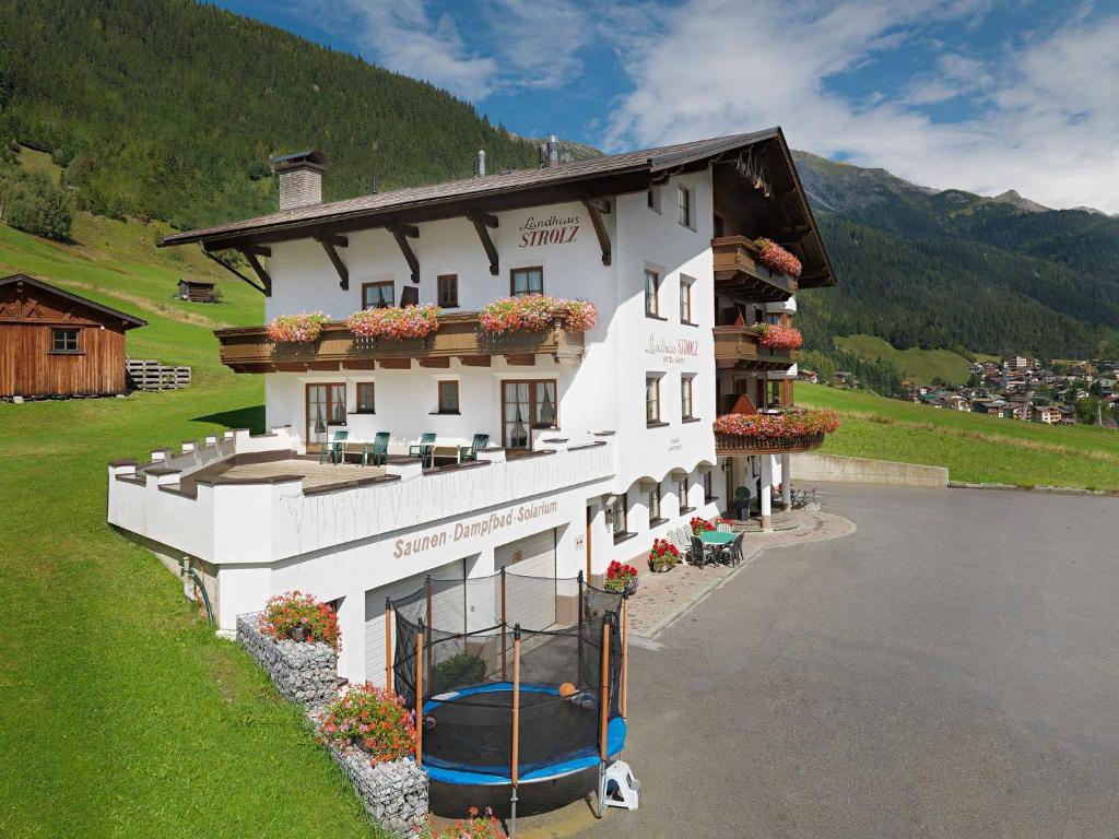 a large white building next to a body of water at Landhaus Strolz in Sankt Anton am Arlberg