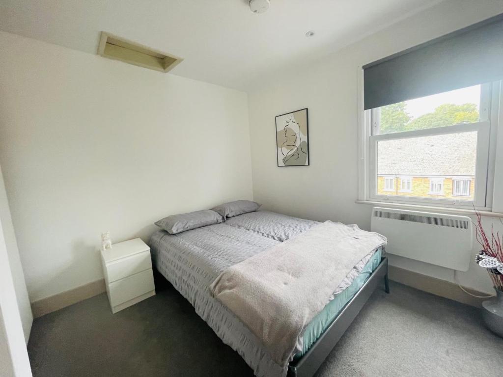 biała sypialnia z łóżkiem i oknem w obiekcie Lovely 1 bedroom apartment in London w Londynie