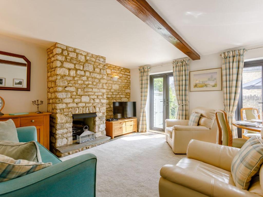 a living room with a stone fireplace and furniture at Stocks Cottage in Blockley