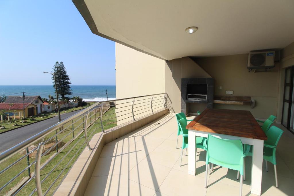 uma varanda com uma mesa e cadeiras e o oceano em Saints View Resort Unit 9 em Uvongo Beach