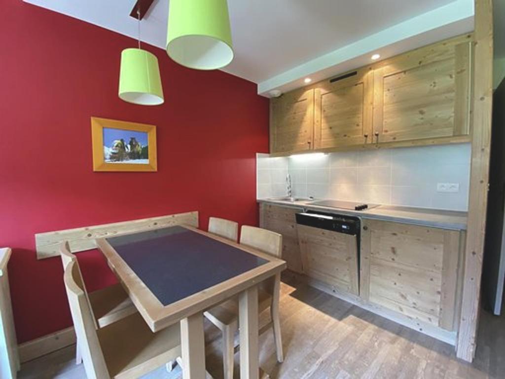 a kitchen with red walls and a wooden table and chairs at Appartement La Tania, 2 pièces, 5 personnes - FR-1-513-78 in La Tania