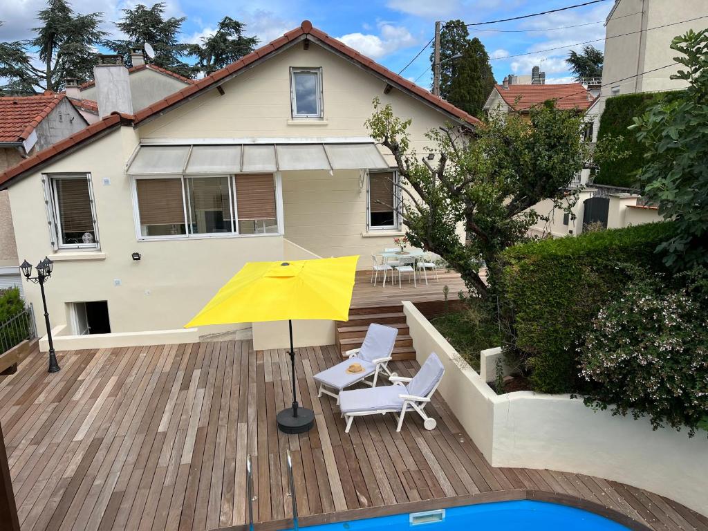 una sombrilla amarilla y 2 sillas en una terraza de madera en À la maison en Saint-Étienne