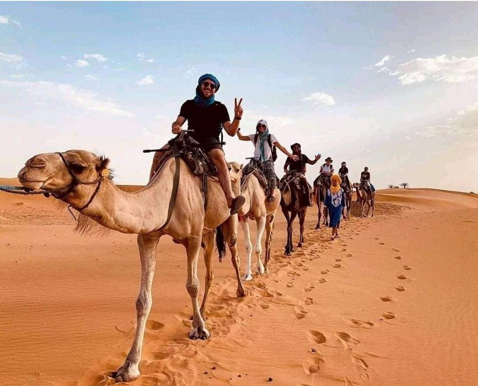 a group of people riding on horses in the desert at Erg Chegaga Camp Excursions in Mhamid