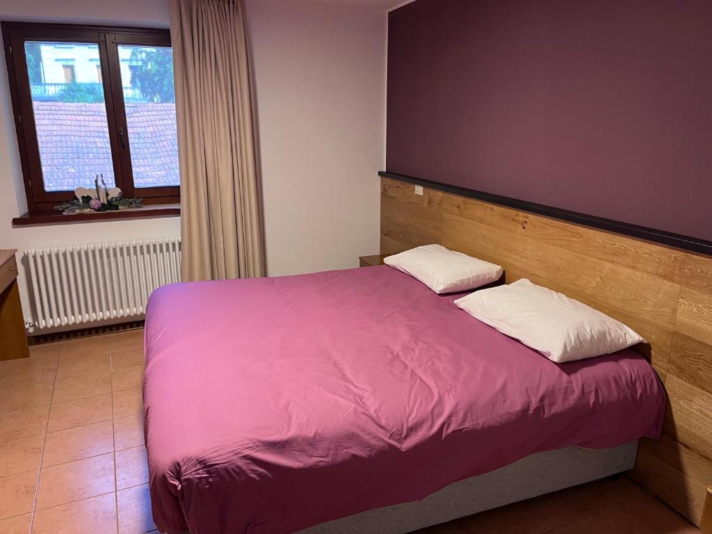 a bedroom with a bed with purple sheets and white pillows at Al Friuli in Nimis