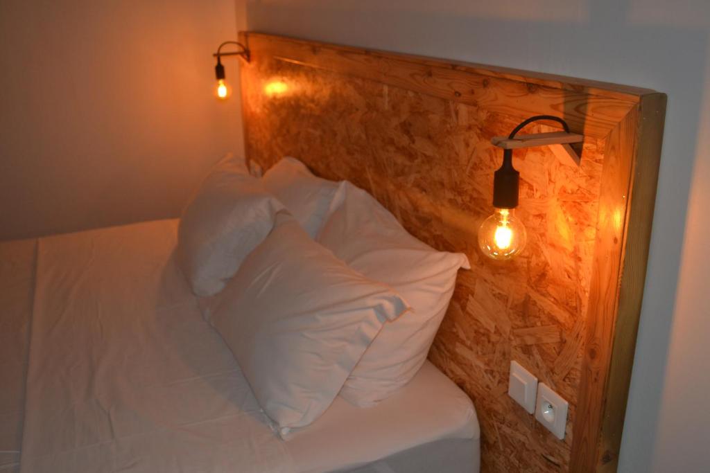 a bed with white pillows and a wall with lights at Plumeria Hébergement Tiare in Grand-Bourg