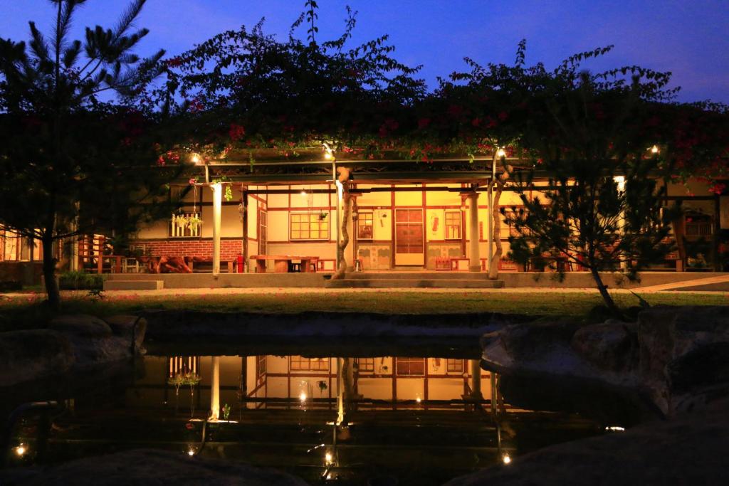 a building with a reflection in the water at night at Inn By Tree in Fujin