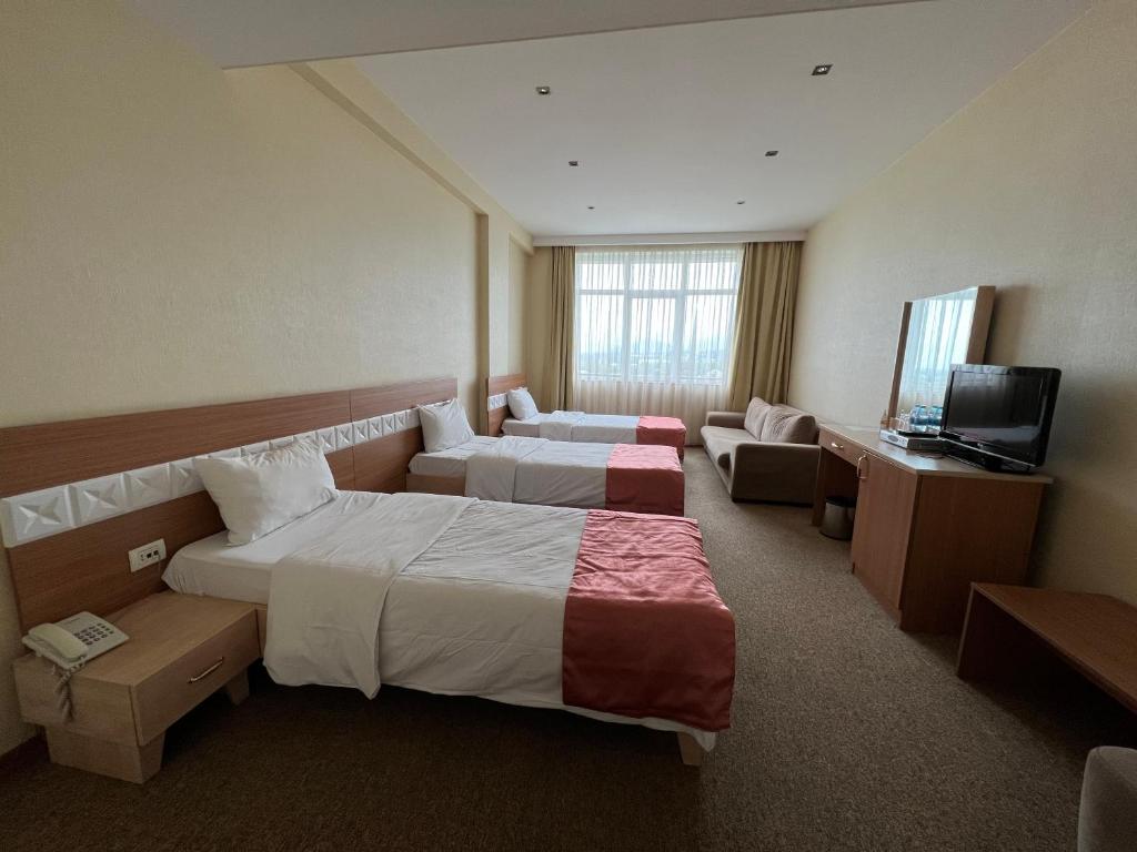 a hotel room with two beds and a television at Gabala Tufandag City Hotel in Gabala