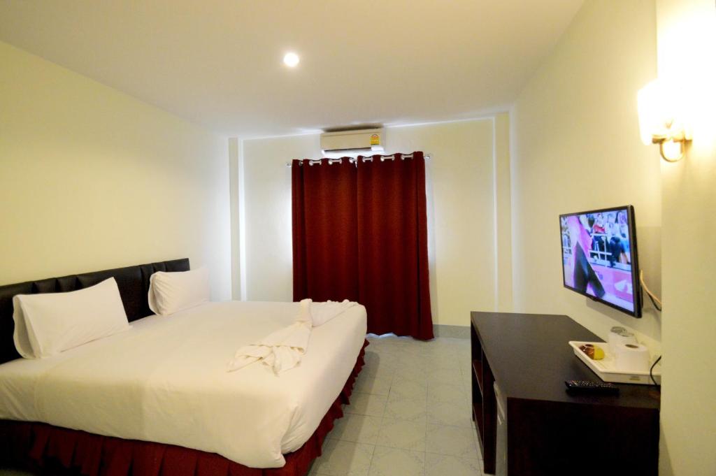 Habitación de hotel con cama y cortina roja en Paripas Express Patong, en Patong Beach