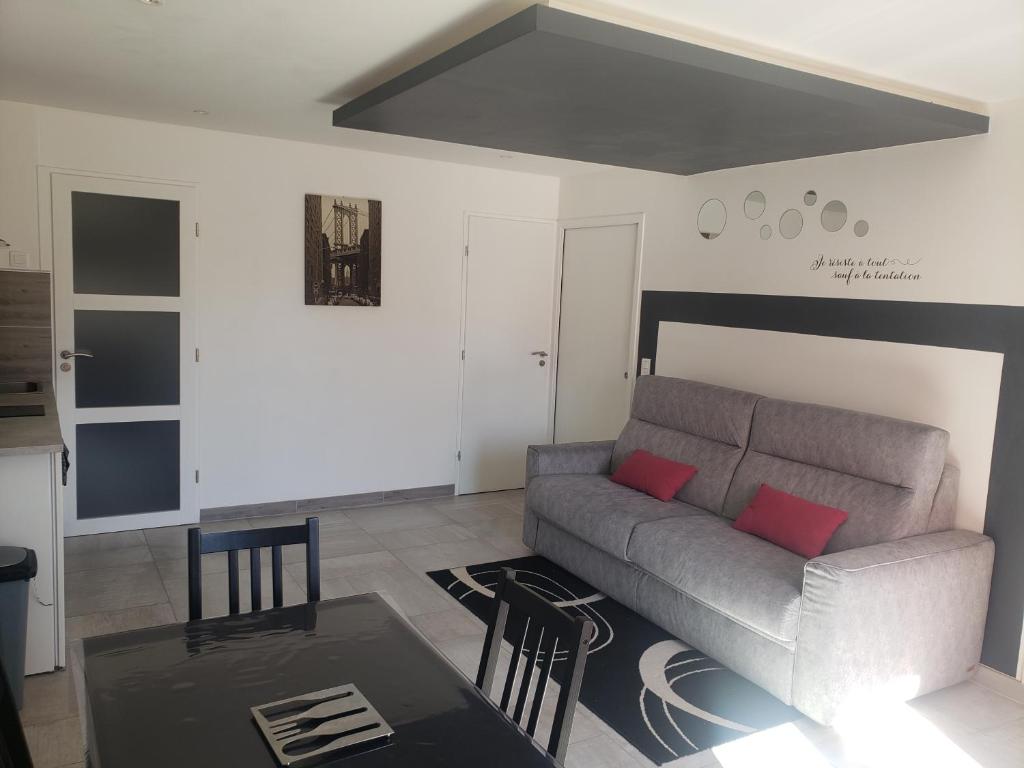 ein Wohnzimmer mit einem Sofa und einem Tisch in der Unterkunft Gîte 2-4 pers avec piscine in La Selle-sur-le-Bied