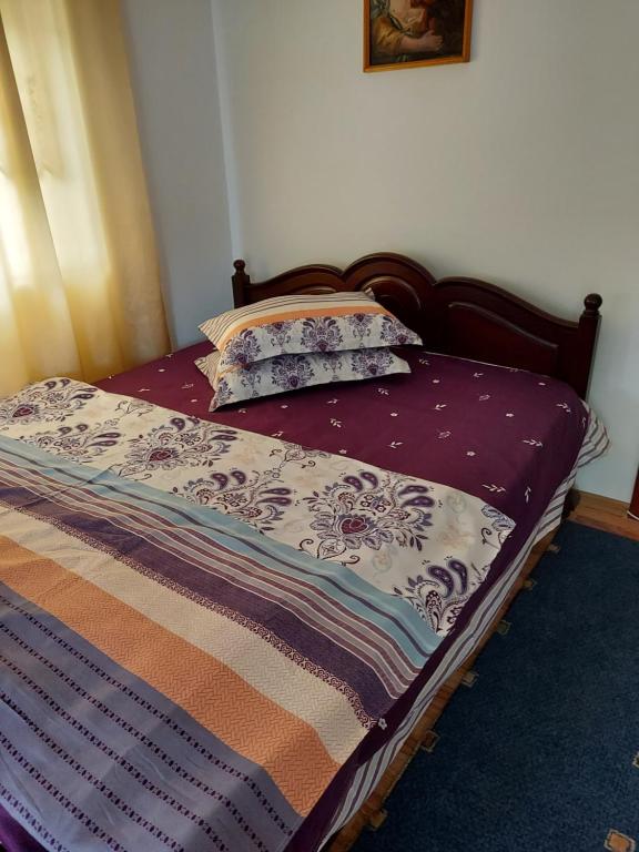 a bed with a purple comforter and two pillows at Casa Rodica in Vatra Dornei