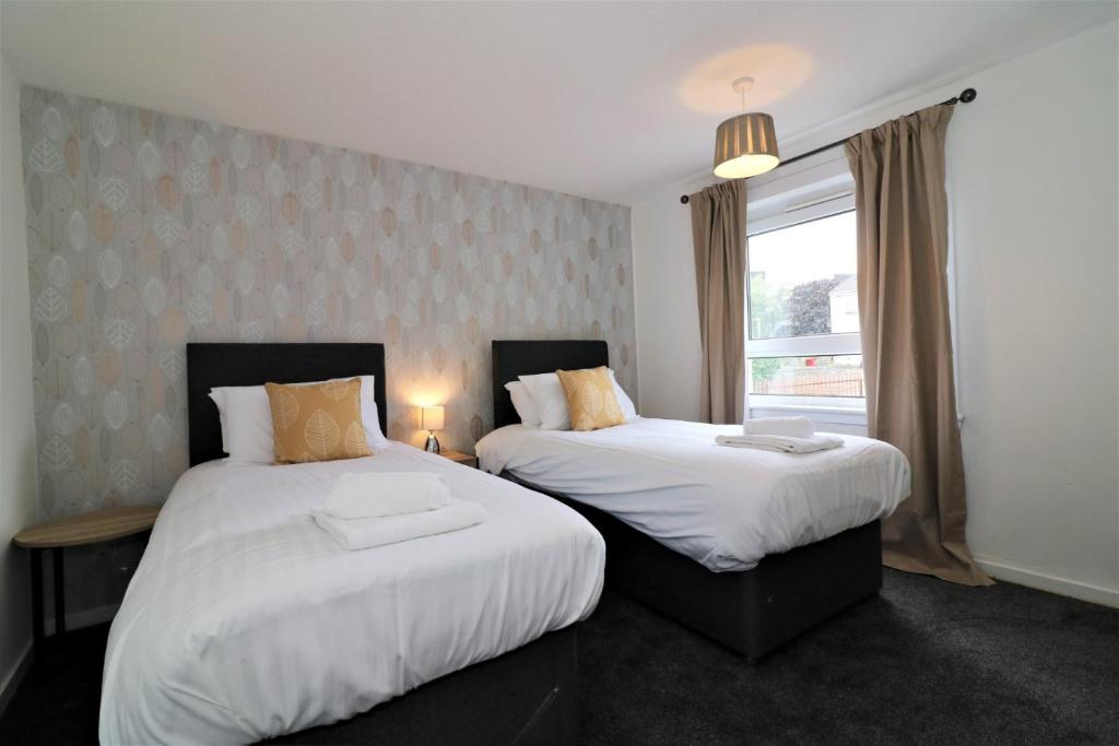 a bedroom with two beds and a window at Signature - Carnoustie House in East Kilbride