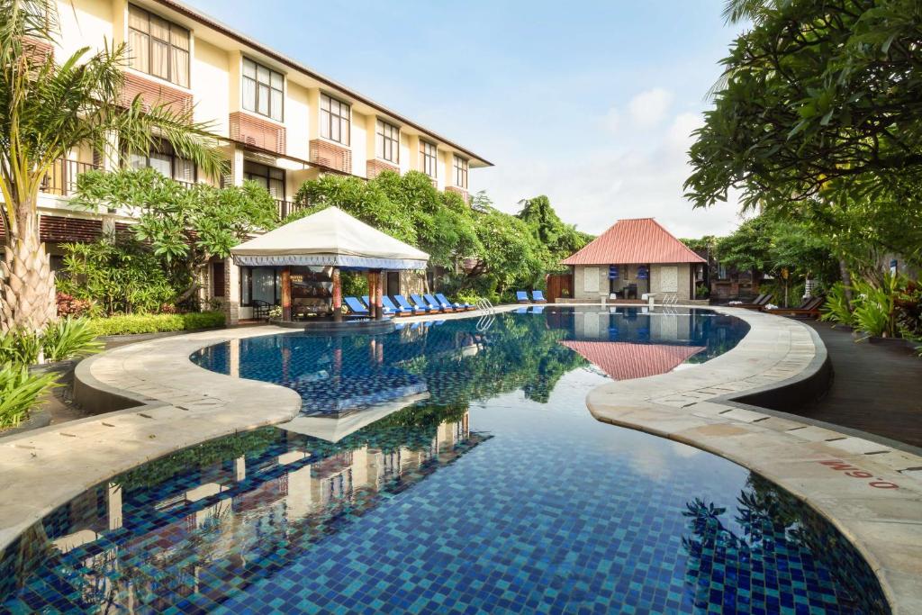 a swimming pool in front of a building at Best Western Resort Kuta in Kuta