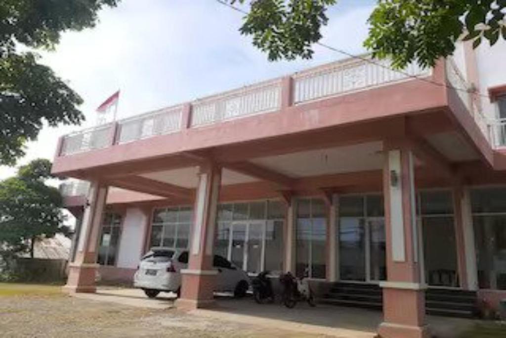 un bâtiment avec une voiture garée devant lui dans l'établissement EXPRESS O 91662 Kost Rumah Kaca, à Mirue