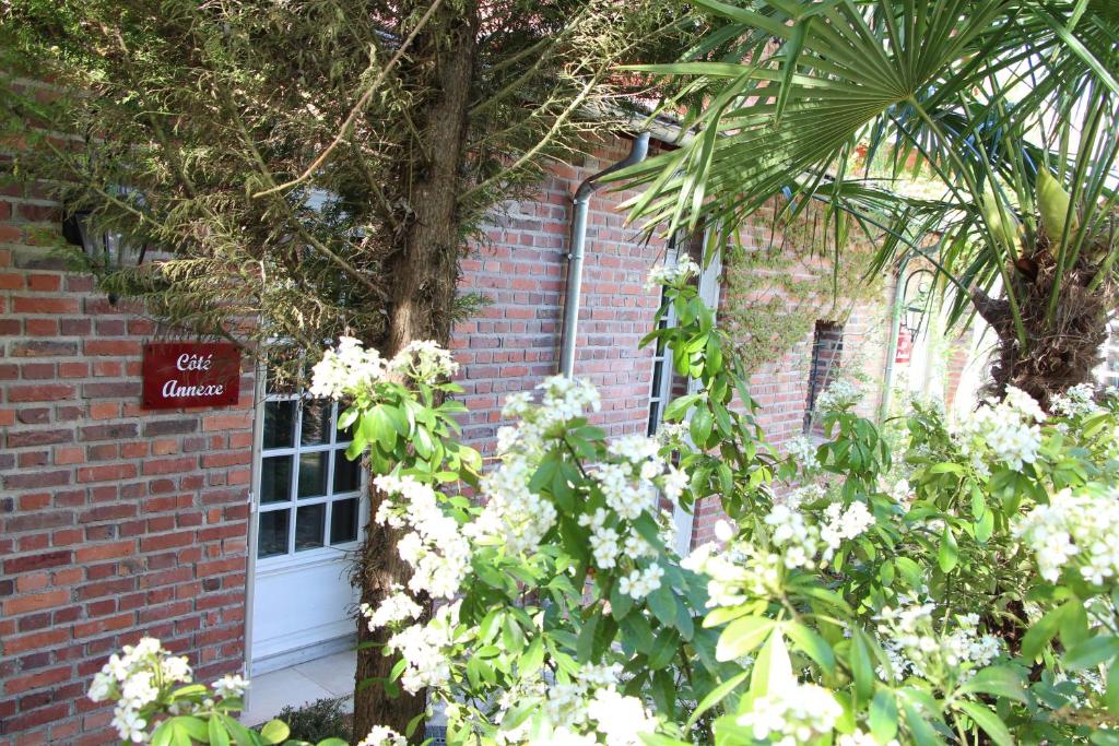 Les Jardins Carnot في كومبيان: مبنى من الطوب مع ورود بيضاء أمام باب