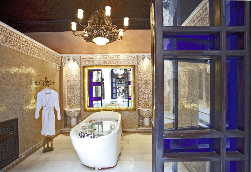 une salle de bain avec une baignoire, un lavabo et un miroir dans l'établissement Palais Shéhérazade & Spa, à Fès