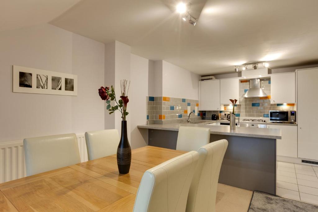 a kitchen with a table with a vase of flowers on it at Modern Spacious Apartments in Bishops Stortford