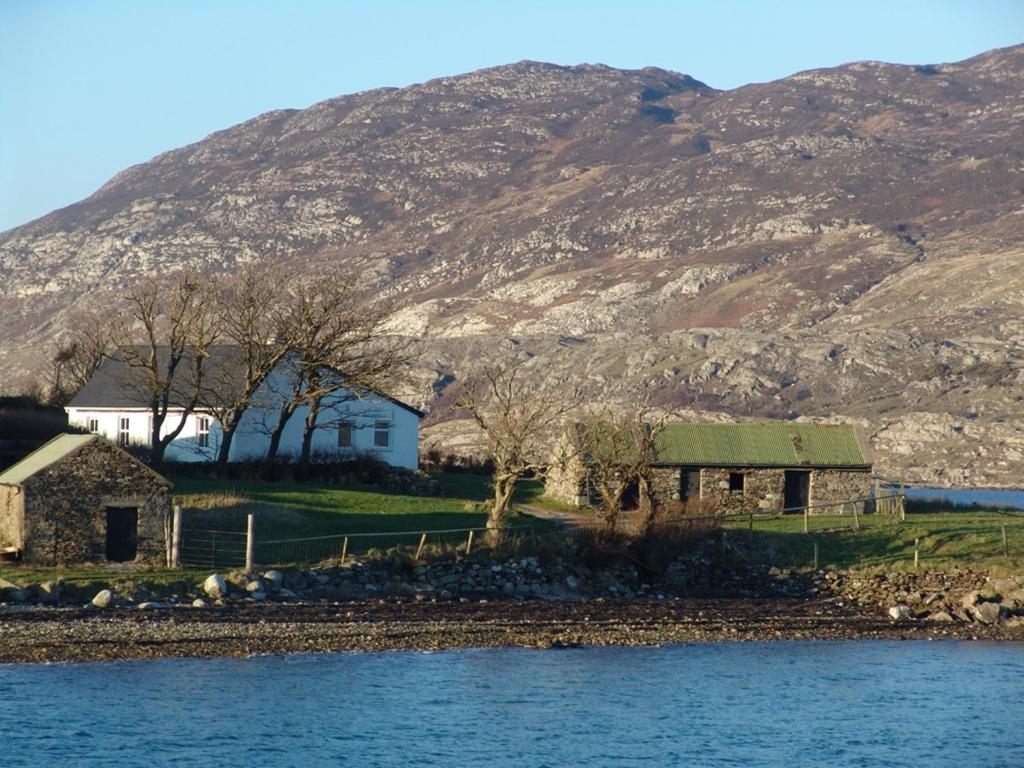 a house with a green roof next to a mountain at Cottage 101 - Moyard in Letterfrack