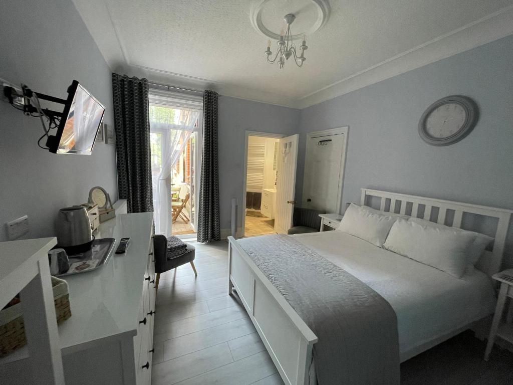1 dormitorio con cama blanca y reloj en la pared en Kates’s Place en Ulwell