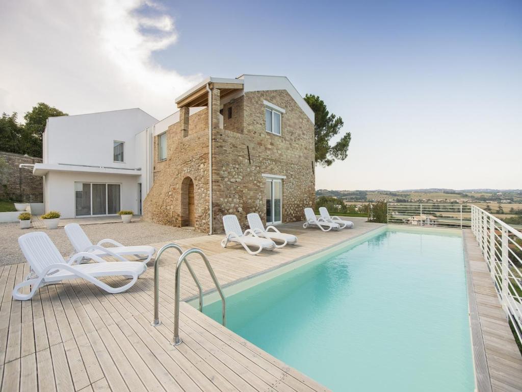 a swimming pool with chairs and a house at Villa Renzo in Notaresco