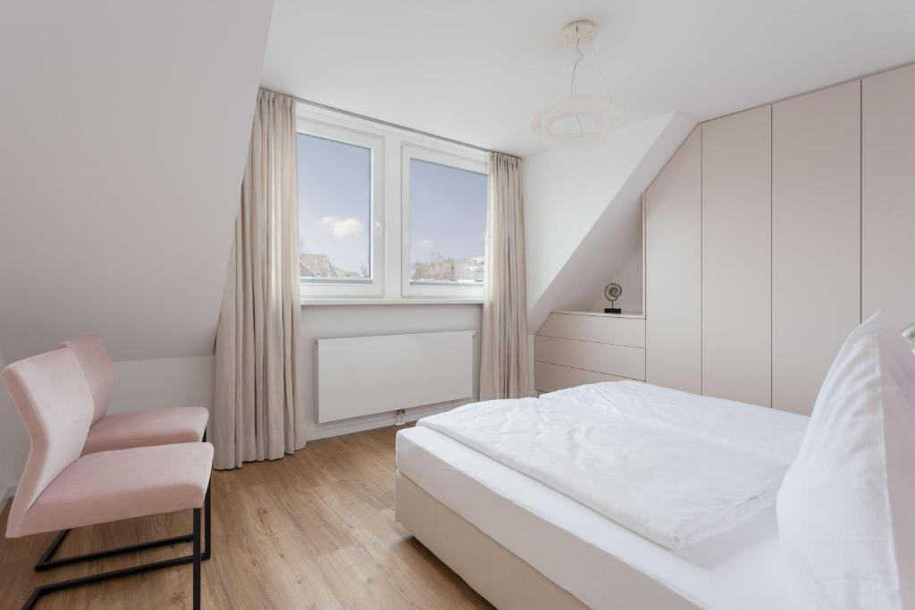 a white bedroom with a bed and a chair at Lieblingshome in Tinnum