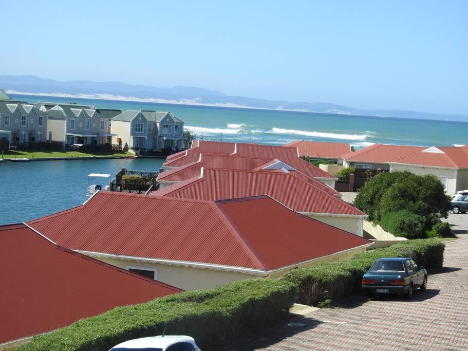 a row of houses with red roofs next to the water at Marina Sands 13A in Jeffreys Bay