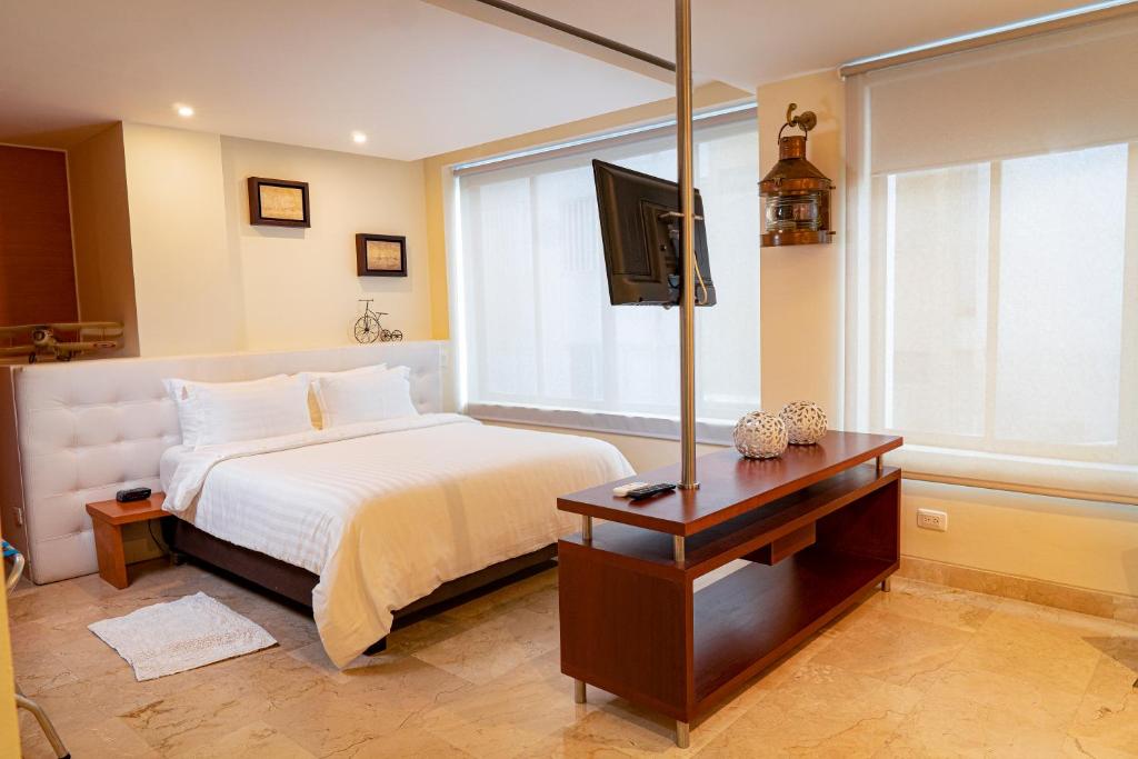 een slaapkamer met een bed en een tafel met een televisie bij PlazaMar Pacifico Hotel in Buenaventura