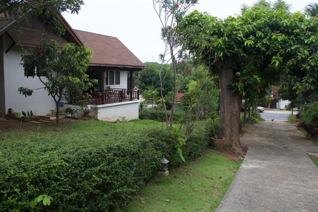 una casa con un albero accanto a un vialetto di บ้านธานี (BAAN THANI) a Choeng Mon Beach