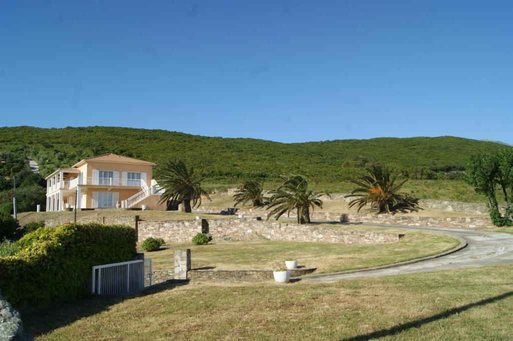 una casa en una colina con palmeras y una carretera en Vue sur mer à Santa Severa - Appartement Les Cyprès 