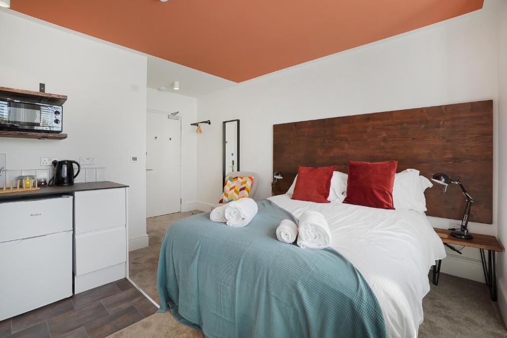 a bedroom with a large white bed with red pillows at Stylish Eco Aparthotel in Folkestone in Folkestone