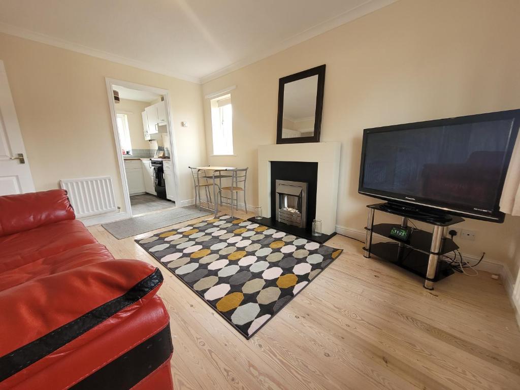 a living room with a fireplace and a television at Lovely 2 bed appt with parking only 5 mins from M6 or Carlisle in Carlisle