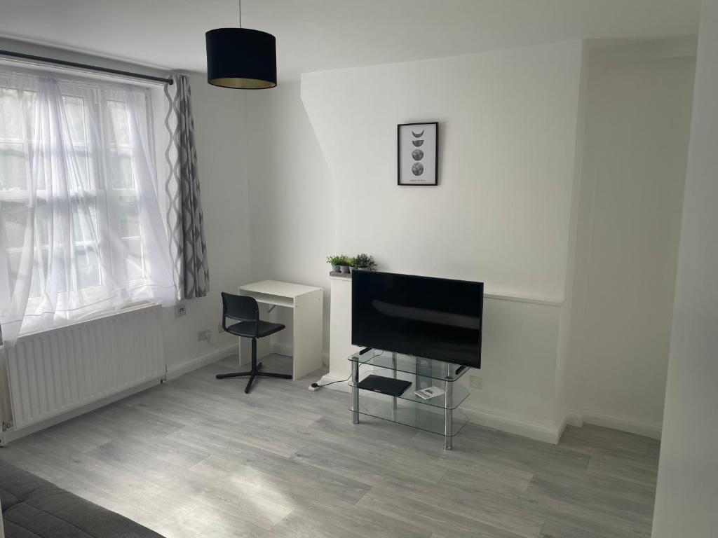 uma sala de estar com uma televisão de ecrã plano e uma secretária em one bedroom flat near Vauxhall train station London em Londres