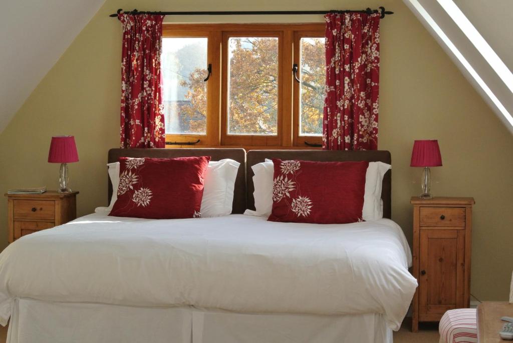 a bedroom with a bed with red pillows and a window at Rosebank B&B in Etchingham
