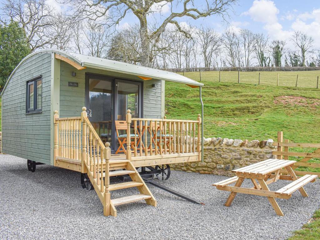 a green tiny house with a porch and a picnic table at The Elm Uk38290 in Crosby Garrett