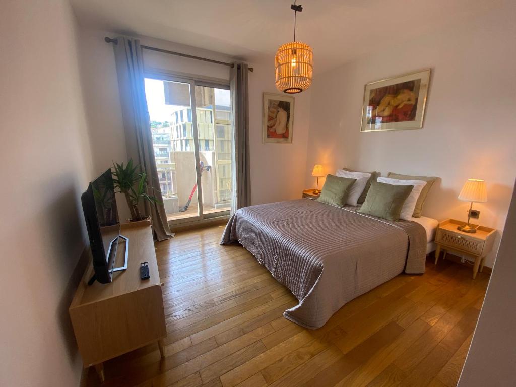 um quarto com uma cama, uma televisão e uma janela em LE BAHIA em Nice