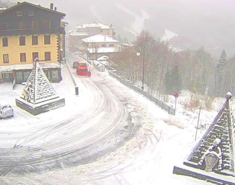 a snowy street with christmas trees and a red car at Casavacanze Abetone in Abetone