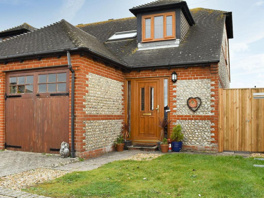 a brick house with a wooden door and a fence at Maverhurst in Earnley