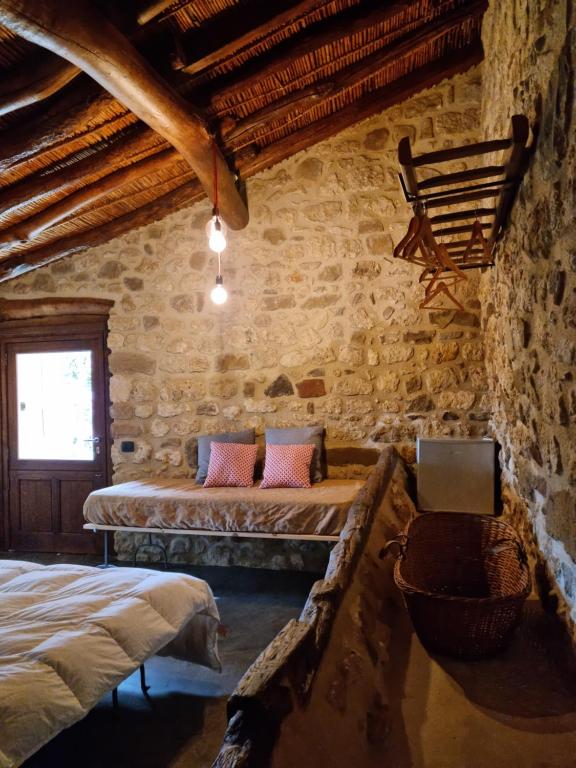 1 dormitorio con 2 camas y TV en una pared de piedra. en Casa Cipampini, en Petralia Soprana