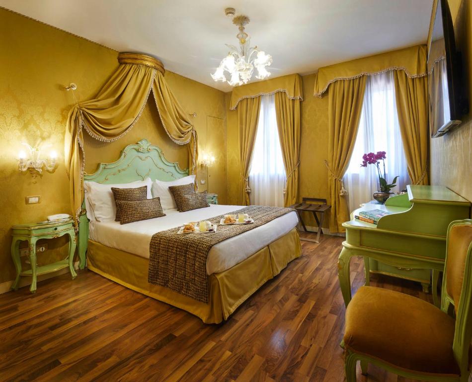 a bedroom with a king sized bed with yellow walls at Hotel Orsaria in Venice