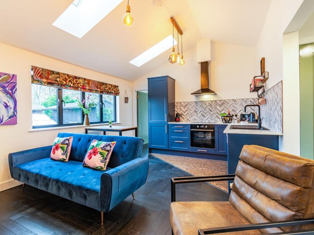 a living room with a blue couch and a kitchen at Lotties Luxurious Lodge - Uk36784 in Sutton Valence