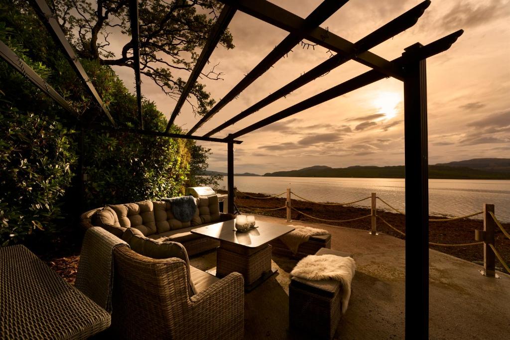 a patio with a table and chairs and a view of the water at Hazelbank, sleeps 10, on the shores of Loch Fyne in Cairndow