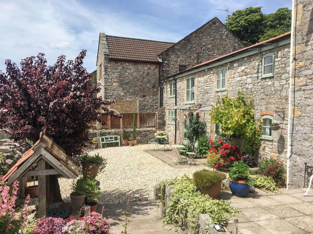 a garden in front of a stone house with flowers at Meadow View-uk34416 in Cheddar