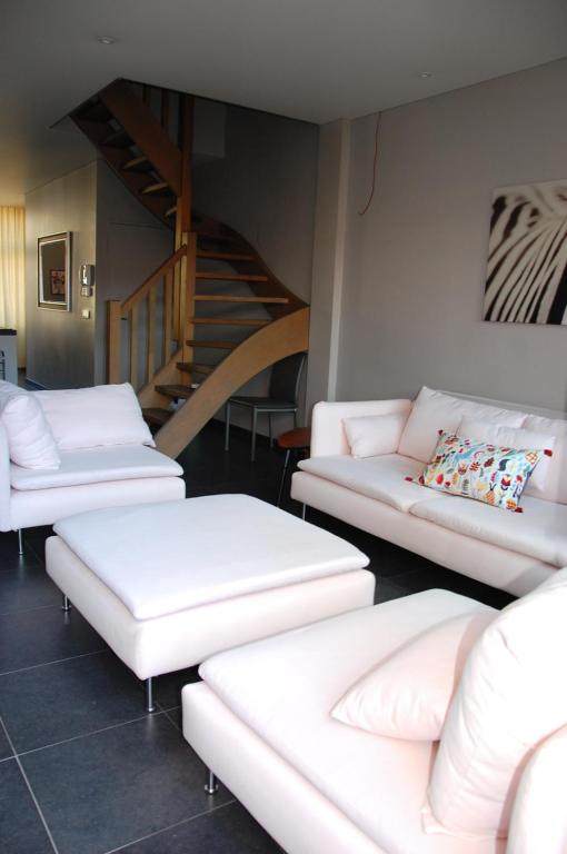 una sala de estar con sofás blancos y una escalera. en Iconique bv Appartement in hartje Ieper, en Ypres
