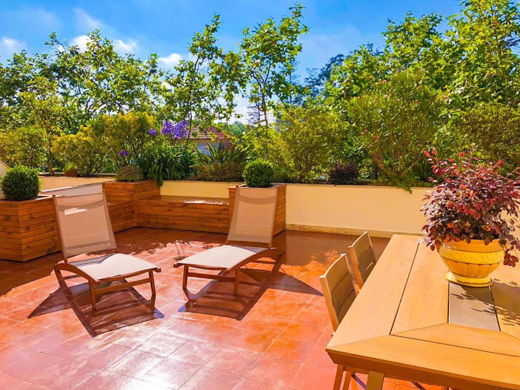 eine Terrasse mit einem Tisch und Stühlen sowie einer Vase mit Blumen in der Unterkunft Charming Home in Sintra Village in Sintra