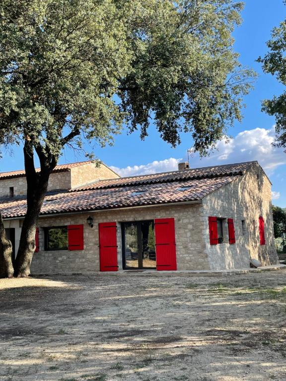 a building with red doors and a tree at Les Néfliers Gîte in Céreste