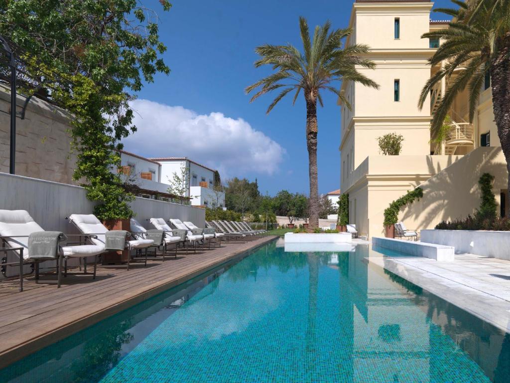 a swimming pool with chairs and a building at Poseidonion Grand Hotel in Spetses