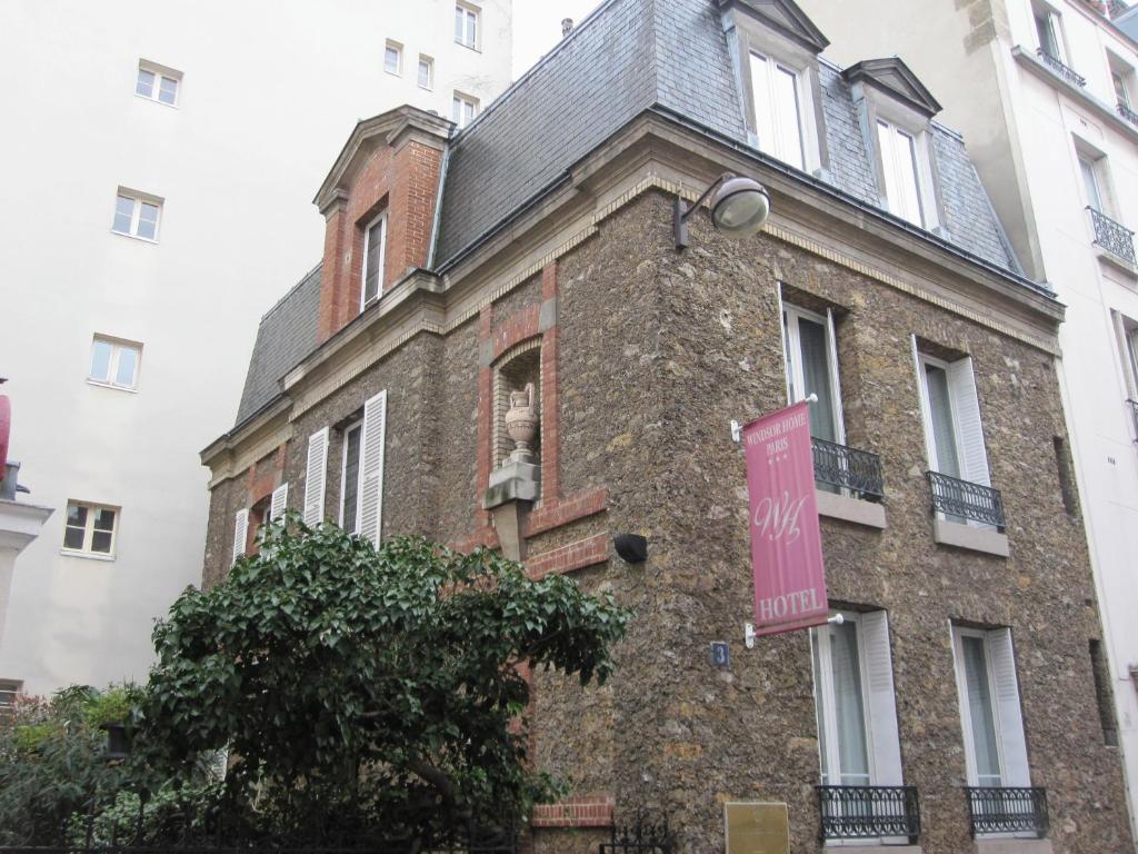un edificio de ladrillo con una señal rosa en él en Hotel Windsor Home en París