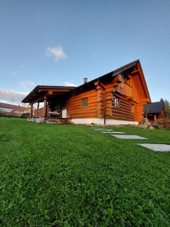 a log cabin with a grass field in front of it at Wellness Srub Jaroměř in Kaplice